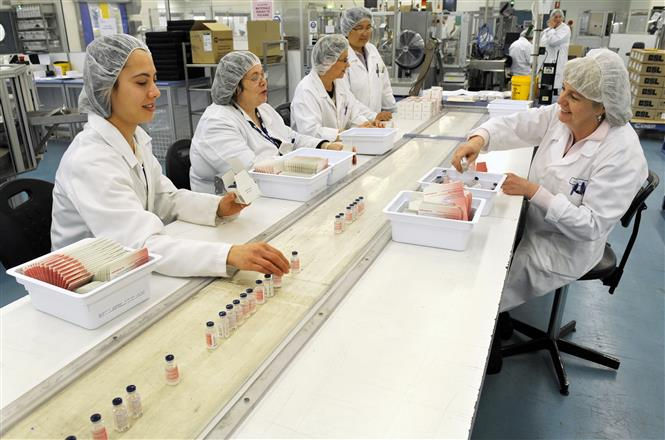   Công nhân làm việc trong dây chuyền sản xuất vắc -xin tại cơ sở của Tập đoàn y tế Australia CSL ở Melbourne. Ảnh: AFP/TTXVN  