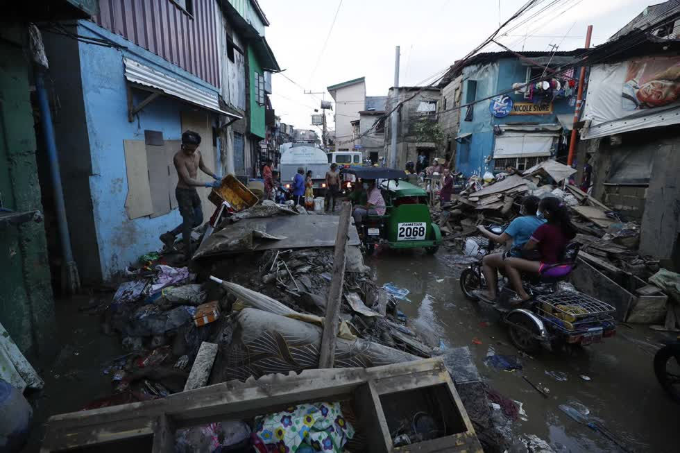  Người dân đi xe qua Marikina, Philippines, hôm 13/11. Bùn dày và mảnh vỡ bao phủ nhiều ngôi làng xung quanh thủ đô Manila của Philippines sau khi cơn bão Vamco gây ra lũ lụt trên diện rộng. Ảnh: AP 