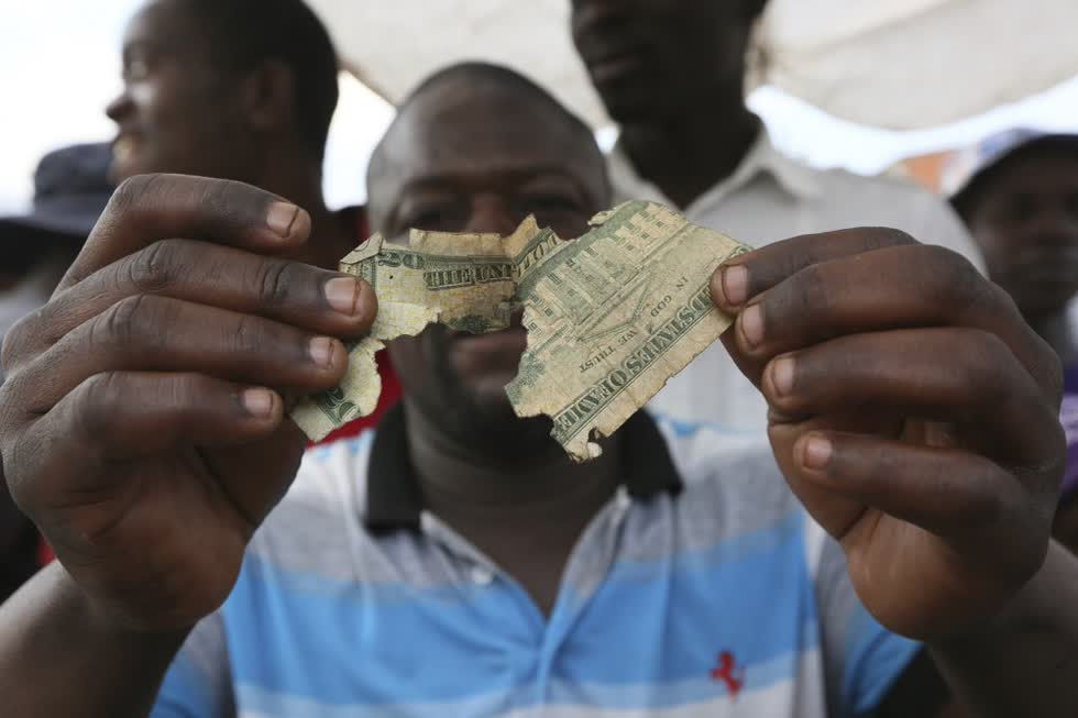 Albert Marombe cầm một tờ 20 đô la rách nát tại một khu chợ sầm uất ở Harare. Ảnh: AP