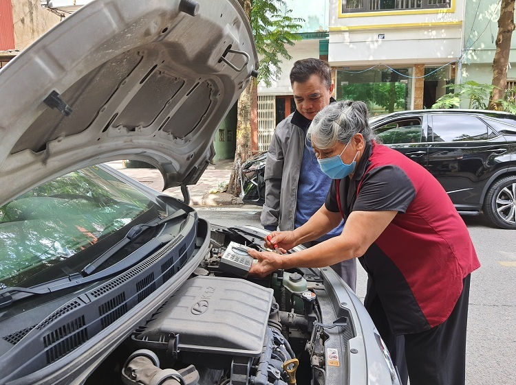 Bà Sâm kiểm tra chất lượng ắc quy và điện cho xe ôtô của ông Đỗ Đình Tự, 58 tuổi, làm nghề lái xe công nghệ. 