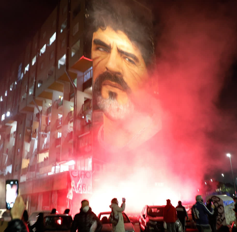 Người hâm mộ Napoli đốt khói đỏ tại một bức tranh tường cho 'người hùng sân cỏ' Maradona của họ trong thành phố. Ảnh: AP