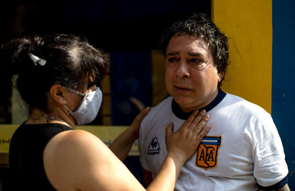 Người vợ an ủi chồng sau bị sốc sau khi nghe tin Maradona qua đời. Ảnh: Getty