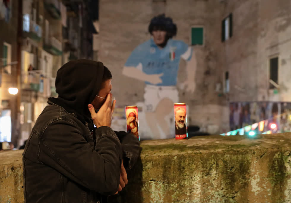 Một fan hâm mộ xúc động, lau nước mắt trước bức tranh tường khổng lồ của ngôi sao bóng đá Maradona. Ảnh: AP