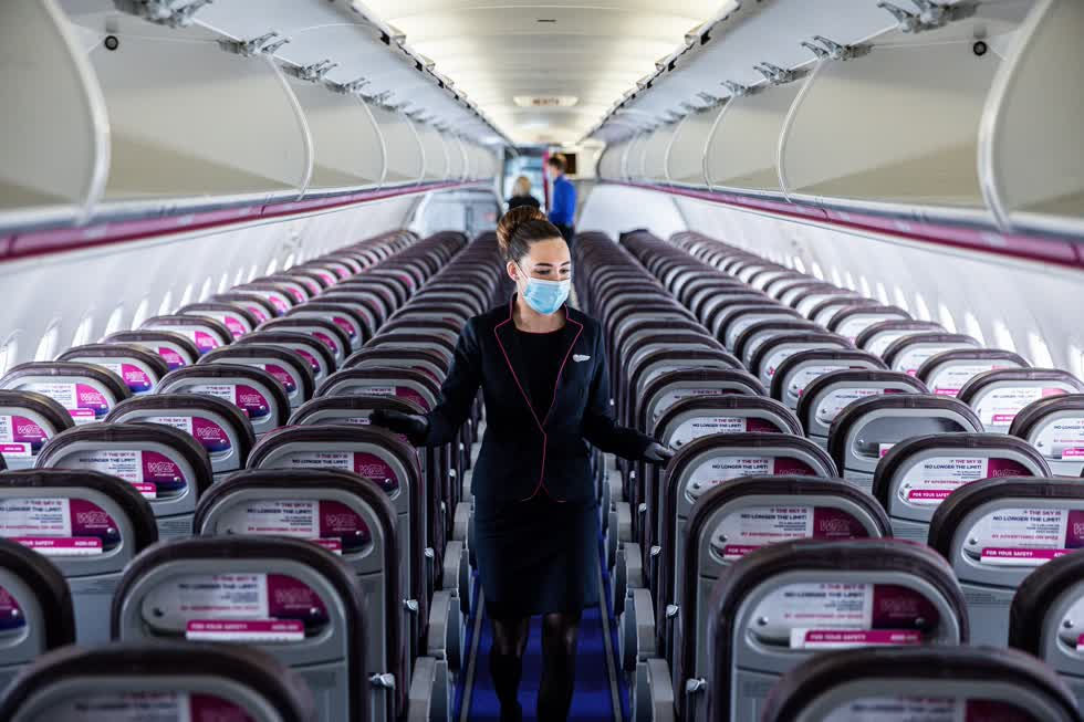Một tiếp viên phi hành đoàn đeo khẩu trang trong lúc kiểm tra chỗ ngồi hành khách trên máy bay tại sân bay Liszt Ferenc ở Budapest, Hungary hồi tháng 5. Ảnh: Bloomberg