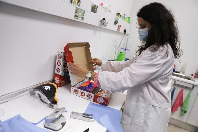   Nhân viên tại nhà máy Science4you mở hộp đồ chơi gồm tấm chắn che giọt bắn làm giảm nguy cơ lây lan virus,… Ảnh: Reuters.  