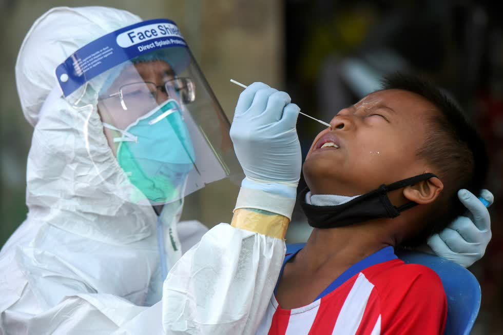 Nhân viên y tế lấy mẫu xét nghiệm COVID-19 cho một bé trai người nhập cư ở chợ hải sản tại tỉnh Samut Sakhon ngày 19/12. Ảnh: Reuters.