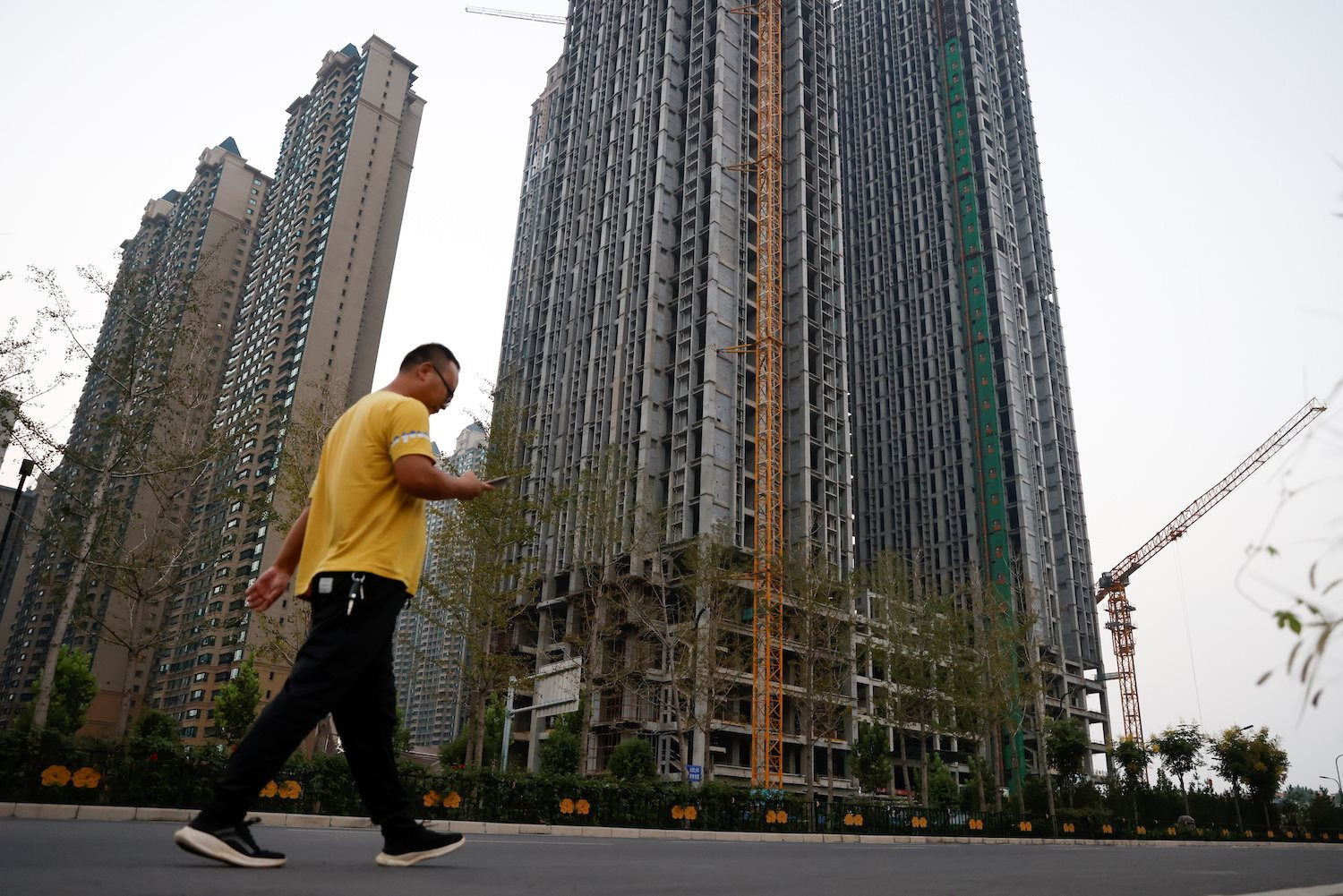 a-man-walks-by-unfinished-residential-blocks-at-the-evergrande-oasis-a-complex-developed-by-evergrande-group-in-luoyang-china-on-sept-15-2021.-rtrscg-rawlins.jpg